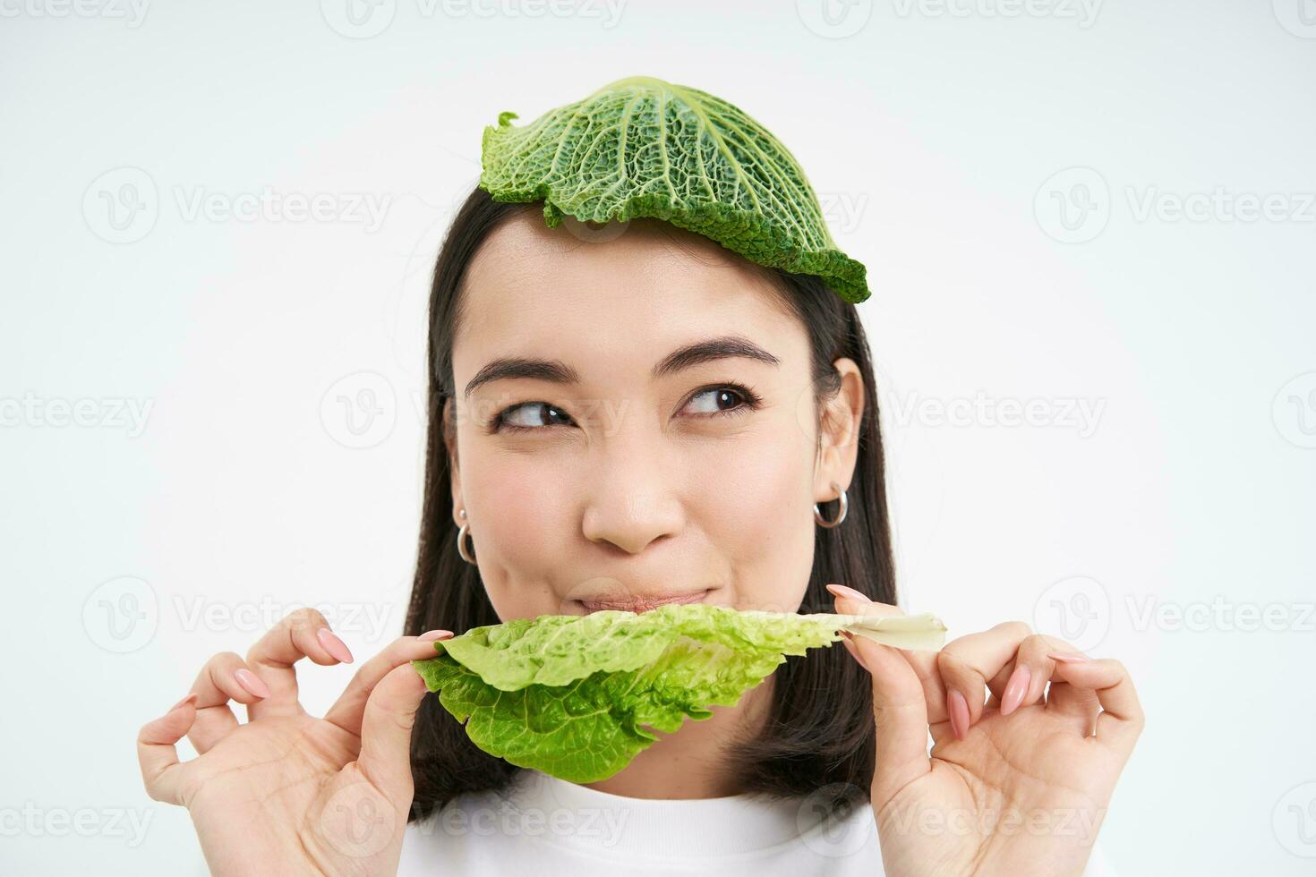 Portrait of asian girl with leaf on head, eats cabbage and smiles, isolated on white background photo