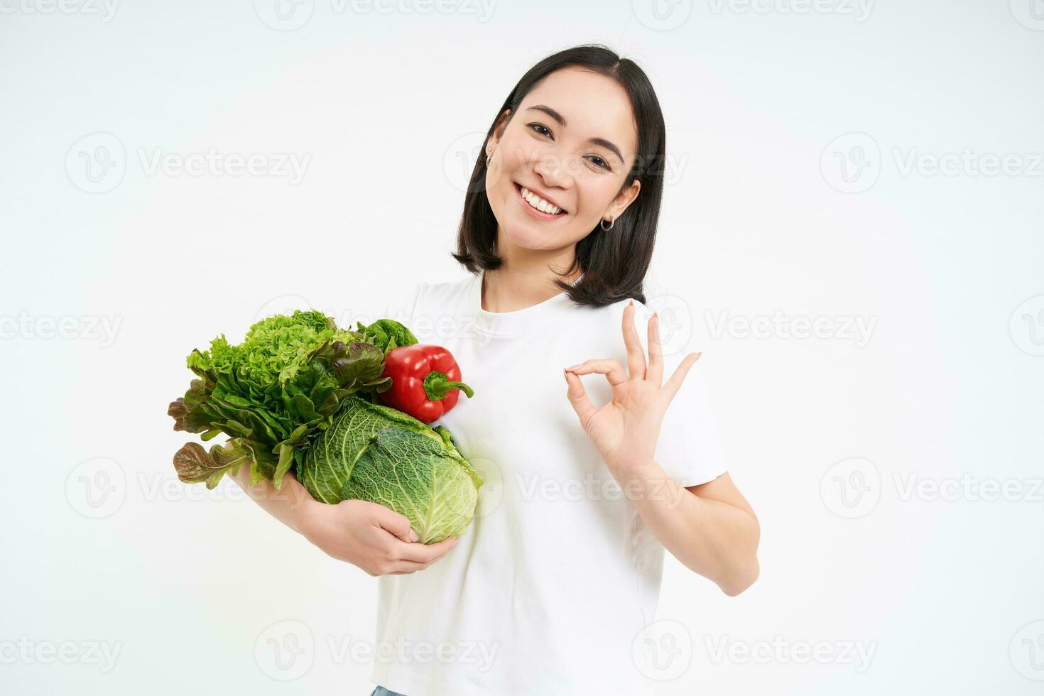 hermosa sonriente mujer, participación verduras, muestra bueno, Okay firmar, aislado en blanco antecedentes foto