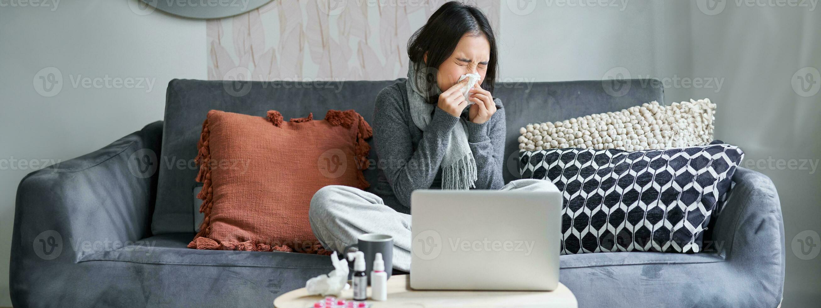 Young asian woman staying at home, feeling unwell, catching a cold, sick leave, sitting with