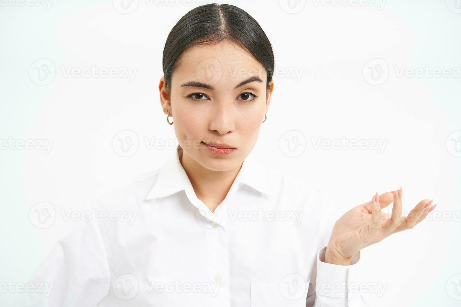Portrait of skeptical asian woman, looks unamused and serious at camera, stands isolated on white background photo