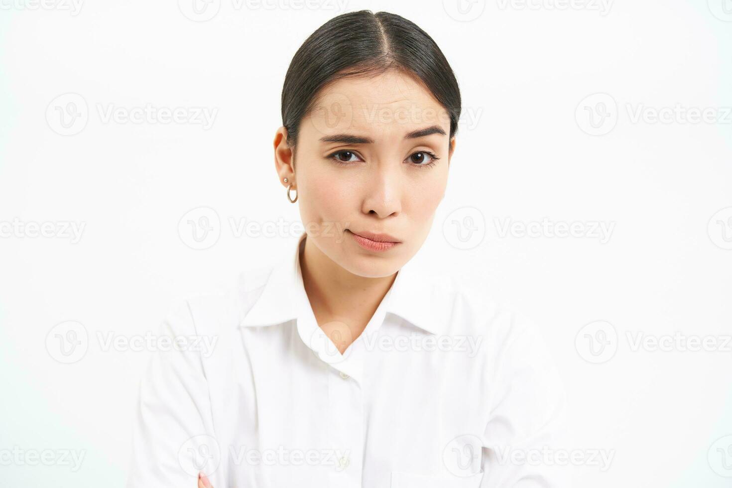 Asian woman professional, looks with skeptical, disbelief face, unsure of smth, stands isolated on white background photo