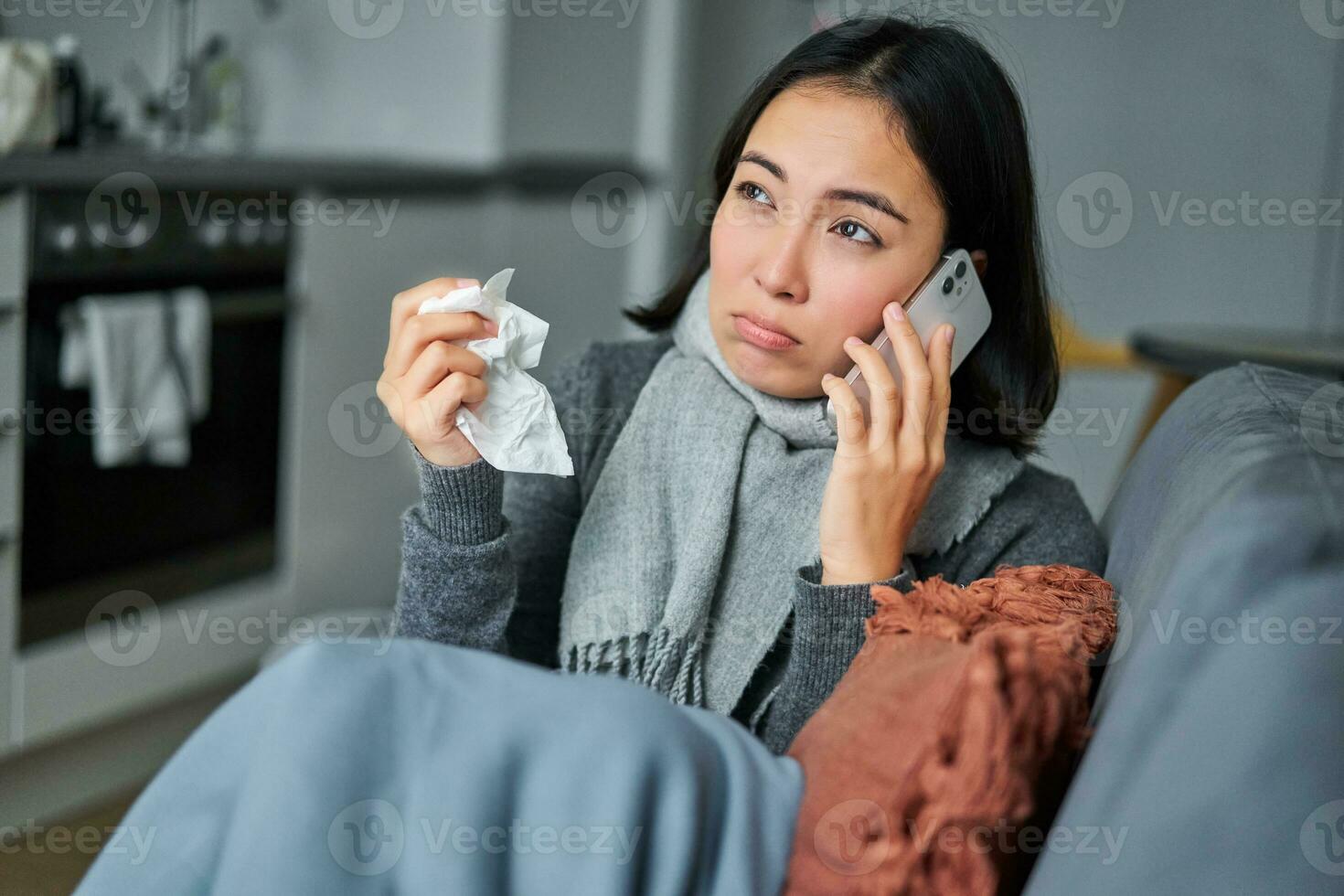 Portrait of sick woman calling her medical clinic, phone call appointment with GP, caught cold and stays at home photo