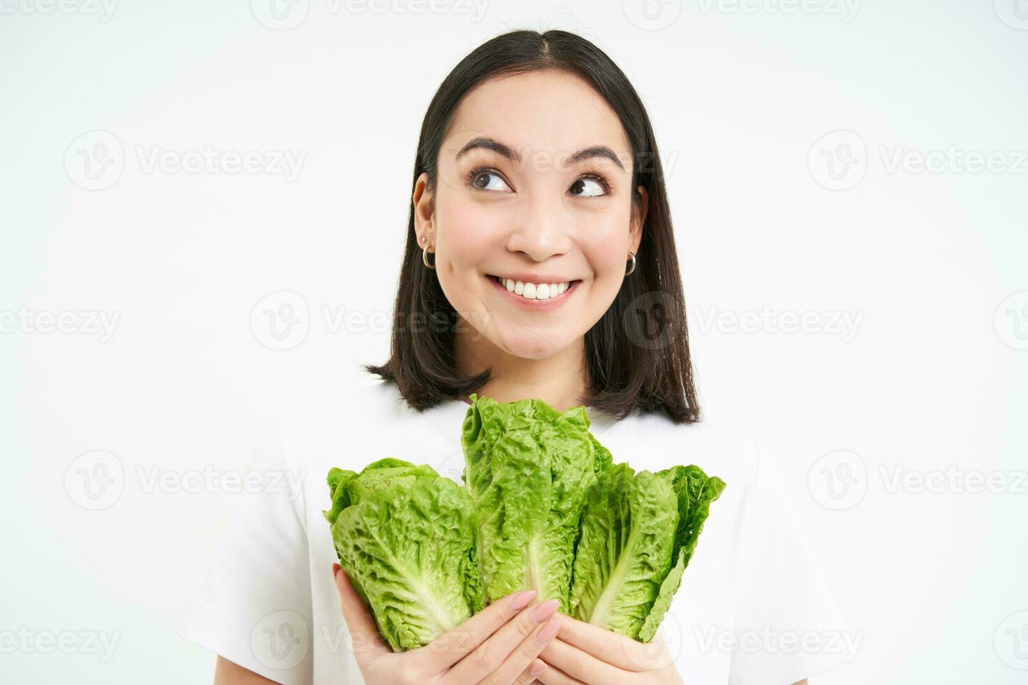 Vegetarian nutrition. Smiling happy young woman looks at her self grown cabbage, eating lettuce