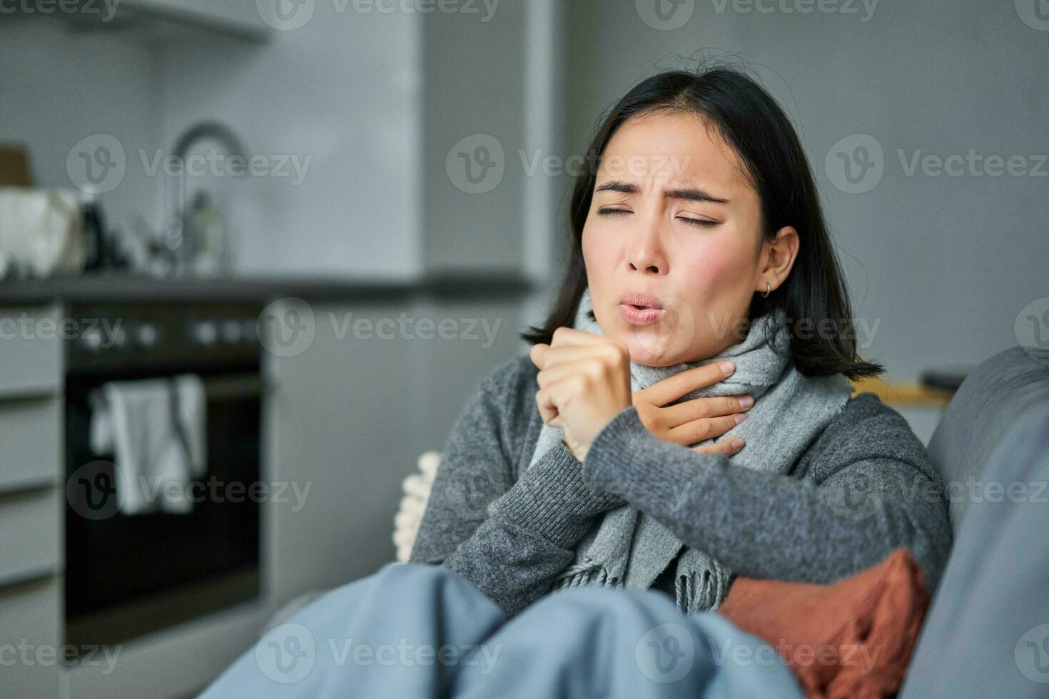 Sick korean woman coughing and feeling unwell, grimacing, has influenza, cought cold or flu, staying at home photo