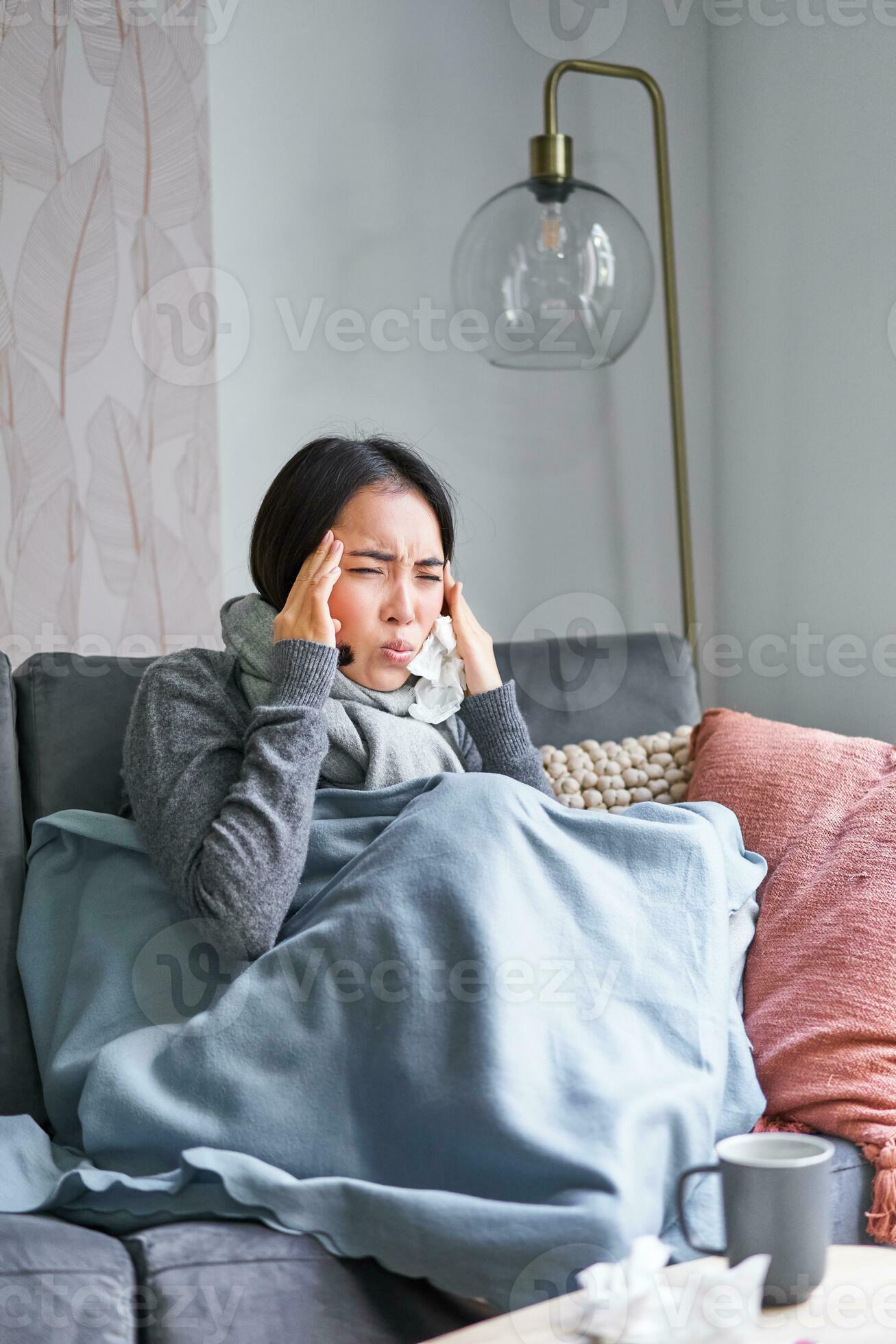 Woman with temperature, coughing, showing symptoms of flu, influenza or cold, sitting in warm