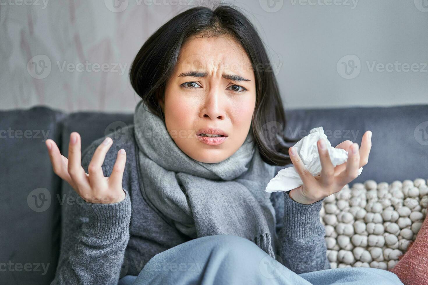Portrait of sad woman feeling unwell, wearing warm clothes and scarf at her home without heating, staying on sick leave in her house photo