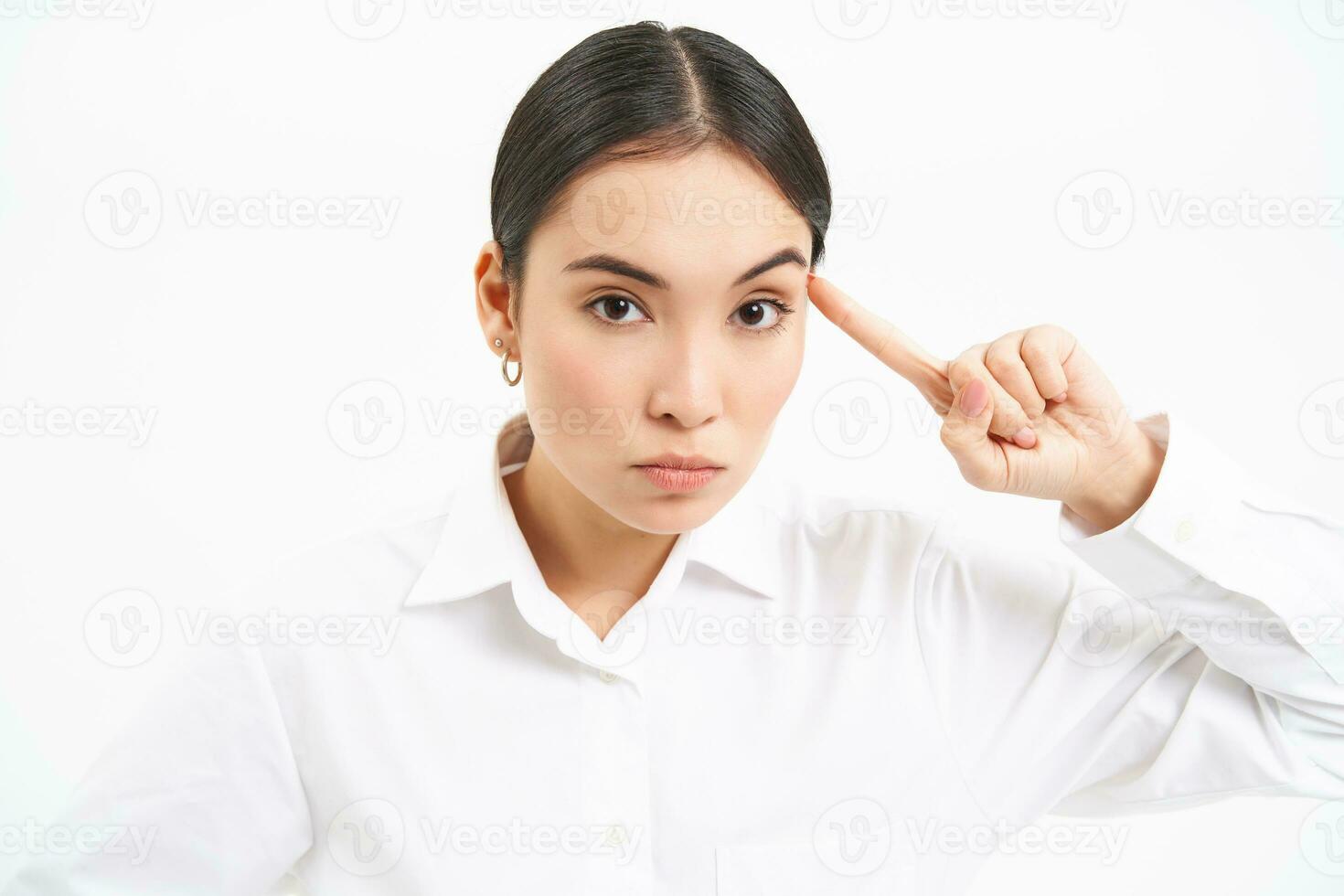 Annoyed team leader, businesswoman points at head, mocks someone, are you crazy gesture, stands over white background photo