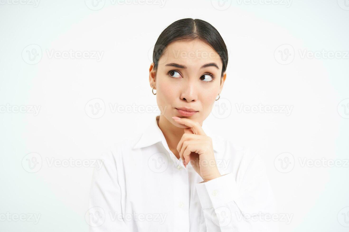 Portrait of businesswoman, asian lady boss thinks, looks thoughtful, pondering something with serious face, standing over white background photo