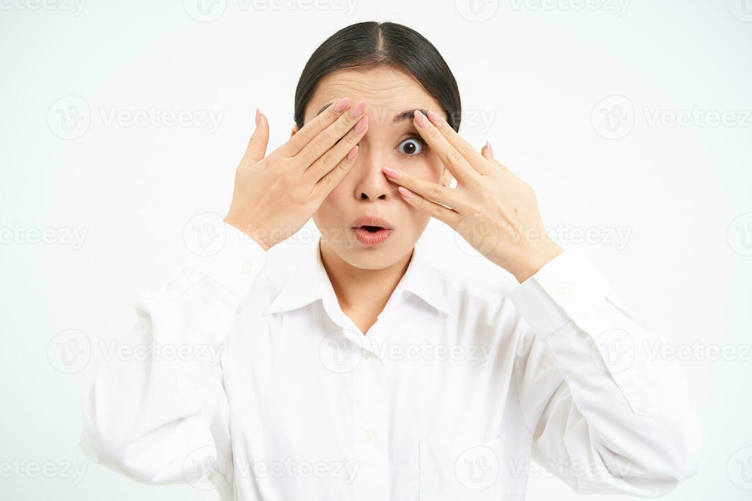 Asian woman entrepreneur, businesswoman shuts her eyes with hands, stands blindfolded against white studio background photo