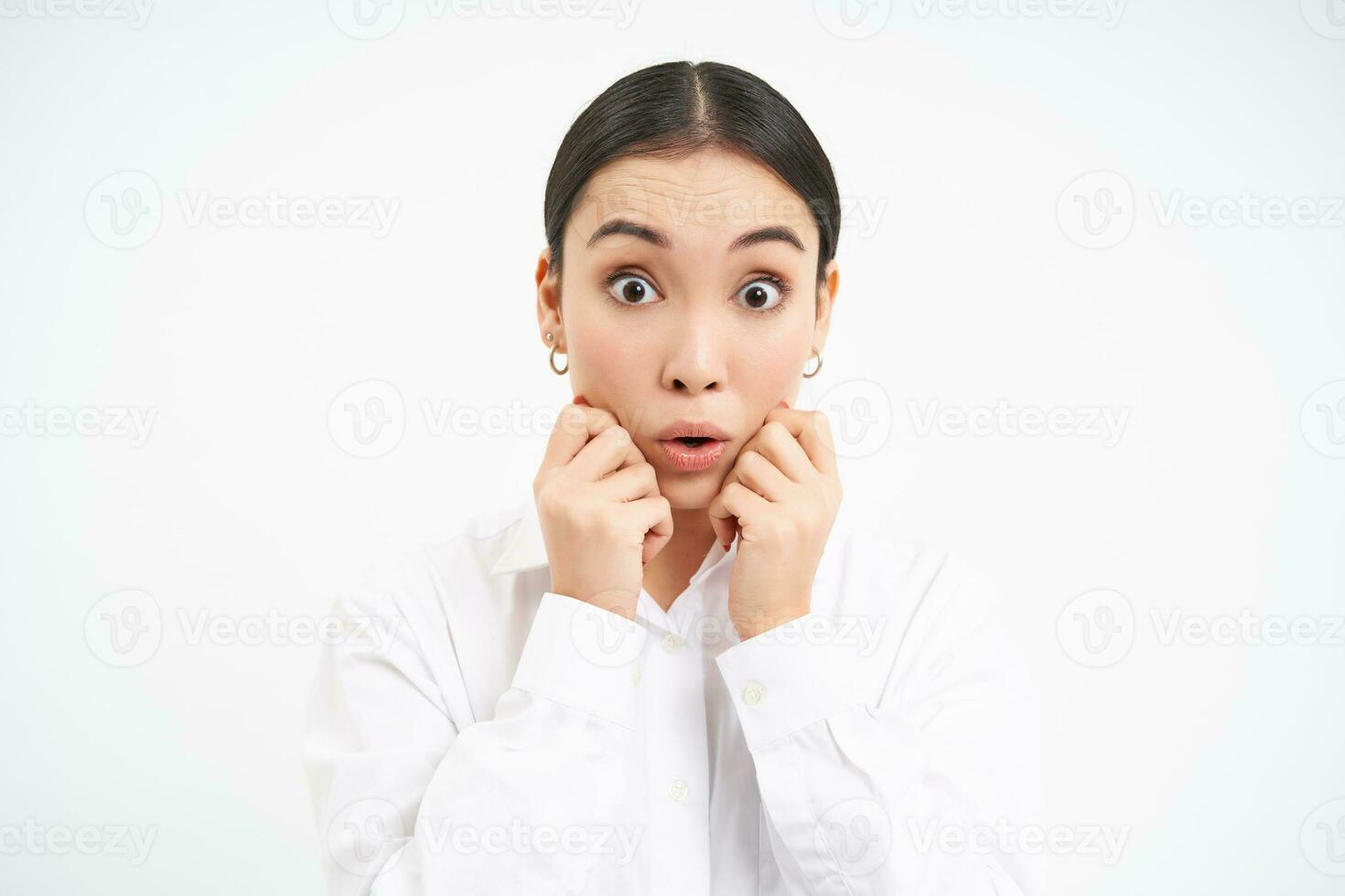 Portrait of asian businesswoman looks surprised, amazed reaction on advertisement, stands over white background photo