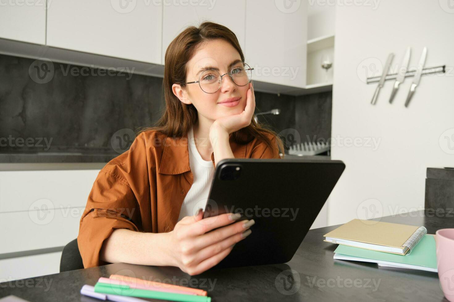 retrato de linda joven mujer, Lanza libre maestro, sentado en cocina vistiendo anteojos, participación digital tableta, enseñando personas en línea, utilizando artilugio a conectar a lección, trabajando remotamente foto