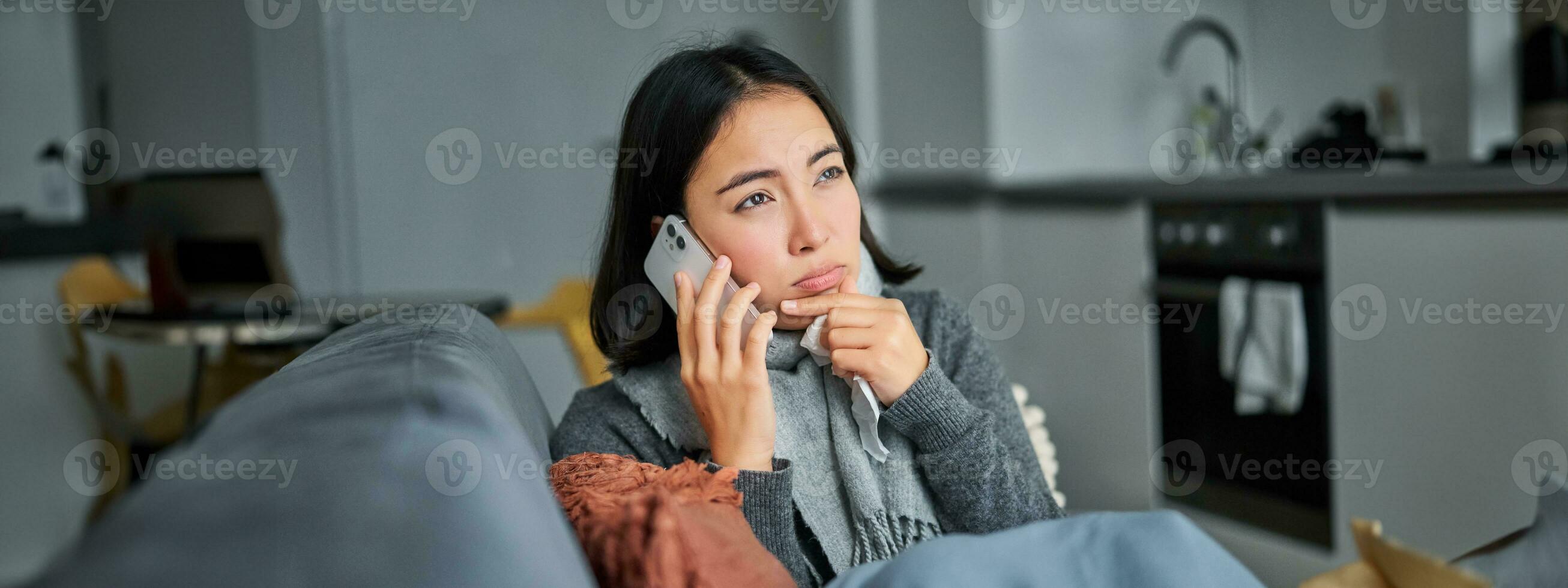 Portrait of sick woman calling her medical clinic, phone call appointment with GP, caught cold and stays at home photo