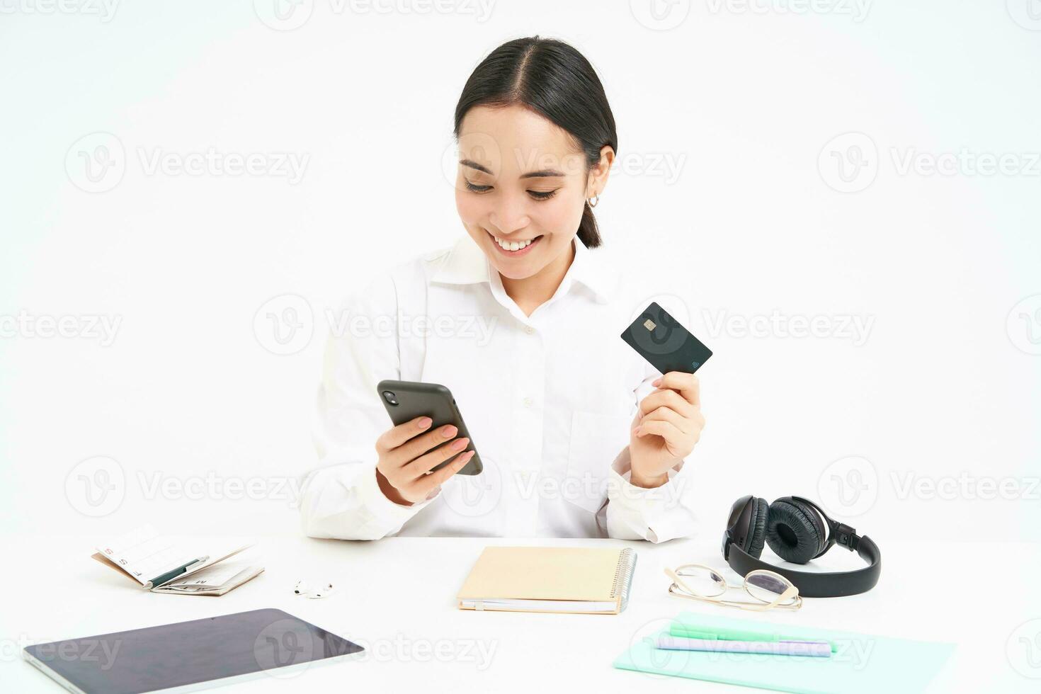 Corporate and business. Asian woman in office, holds smartphone and credit card, paying online, setting up direct debit online, white background photo