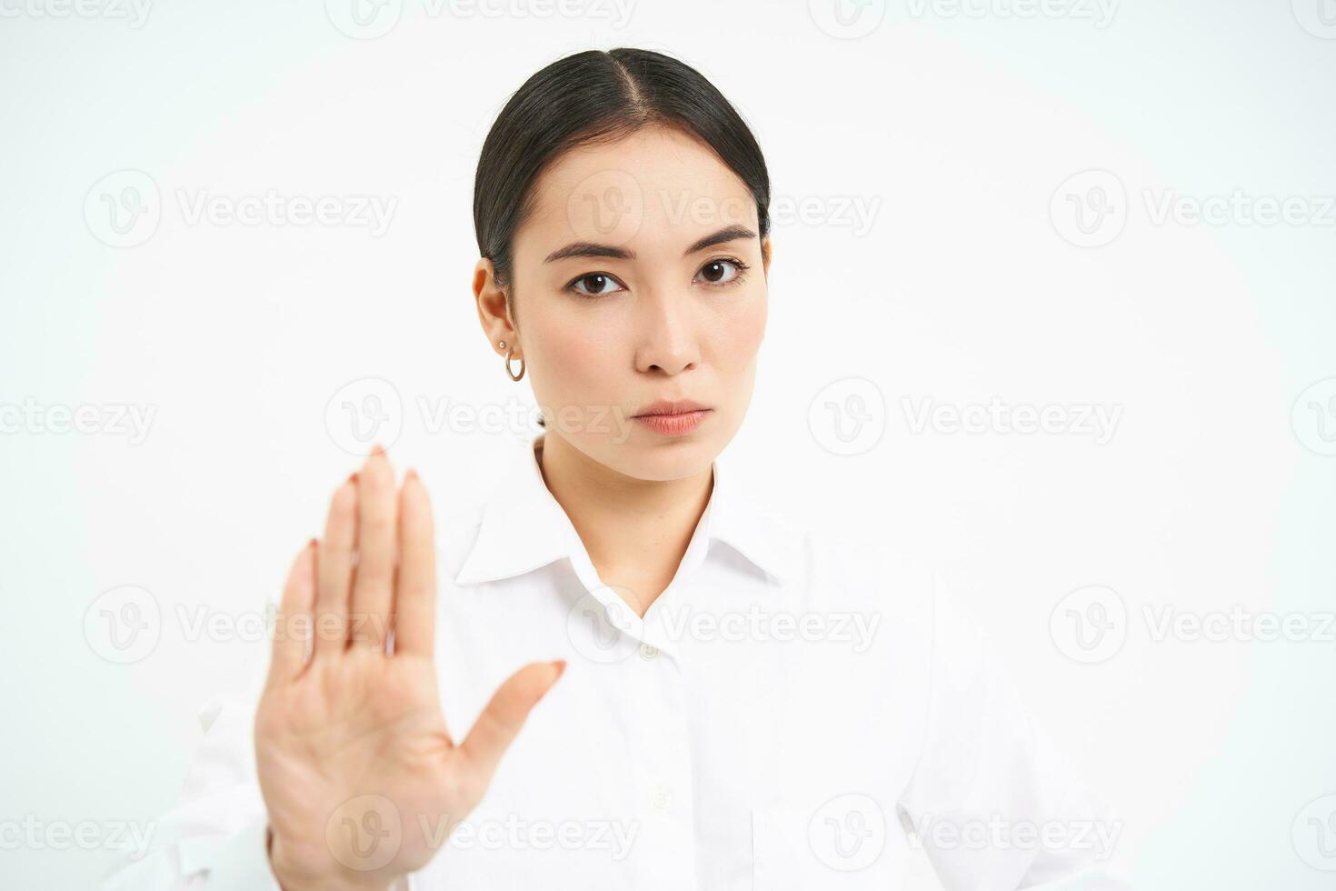 Please stop, enough. Serious asian female manager, businesswoman shows extended hand gesture, disapproves, prohibits smth, white background photo