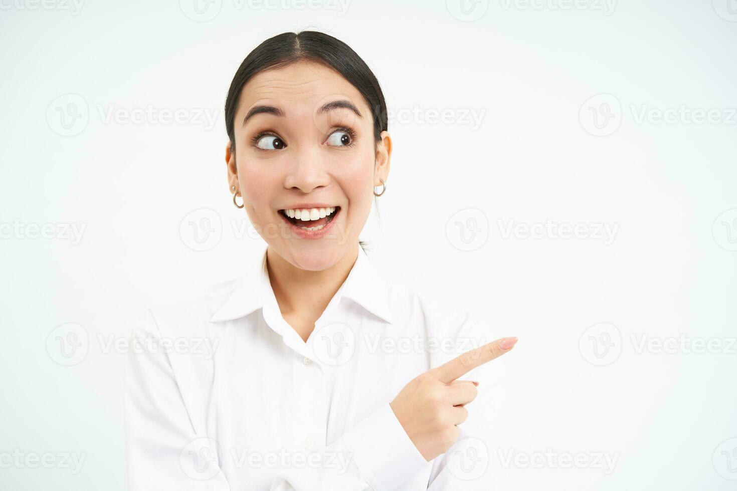 Successful korean businesswoman, pointing finger right, showing advertisement on banner, standing over white background photo