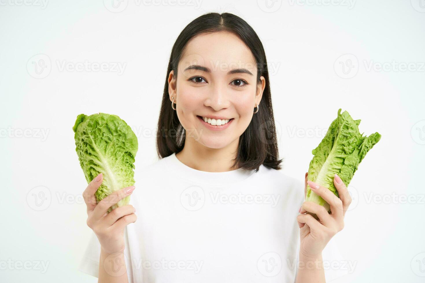 Happy korean woman vegetarian, smiling and showing cabbage, eating lettuce on diet, leads active lifestyle, white background photo