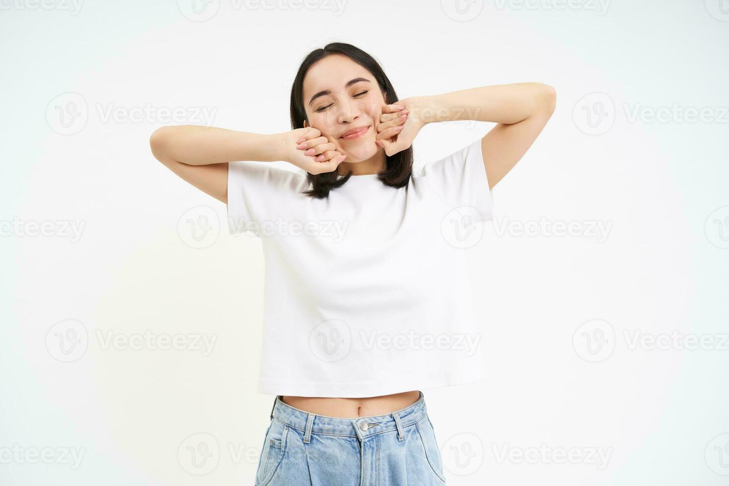 Smiling pleased korean woman, stretching her hands with pleased face, waking up from nap, standing over white background photo