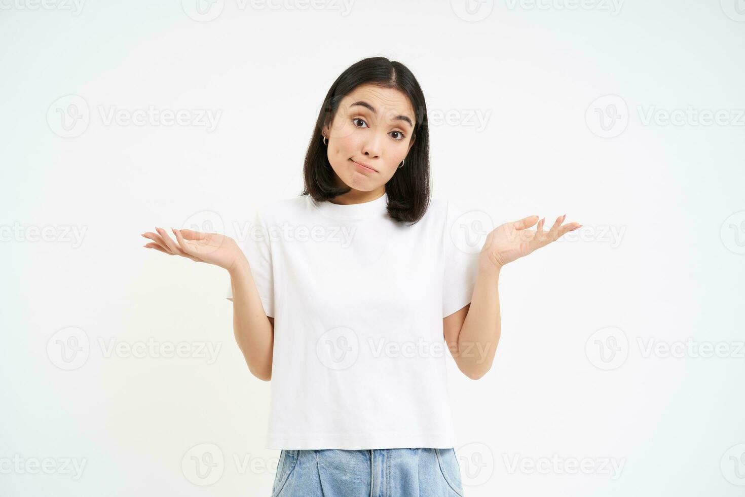 Portrait of confused korean woman, shrugging shoulders, looks puzzled, dont know, has no idea, stands over white background photo