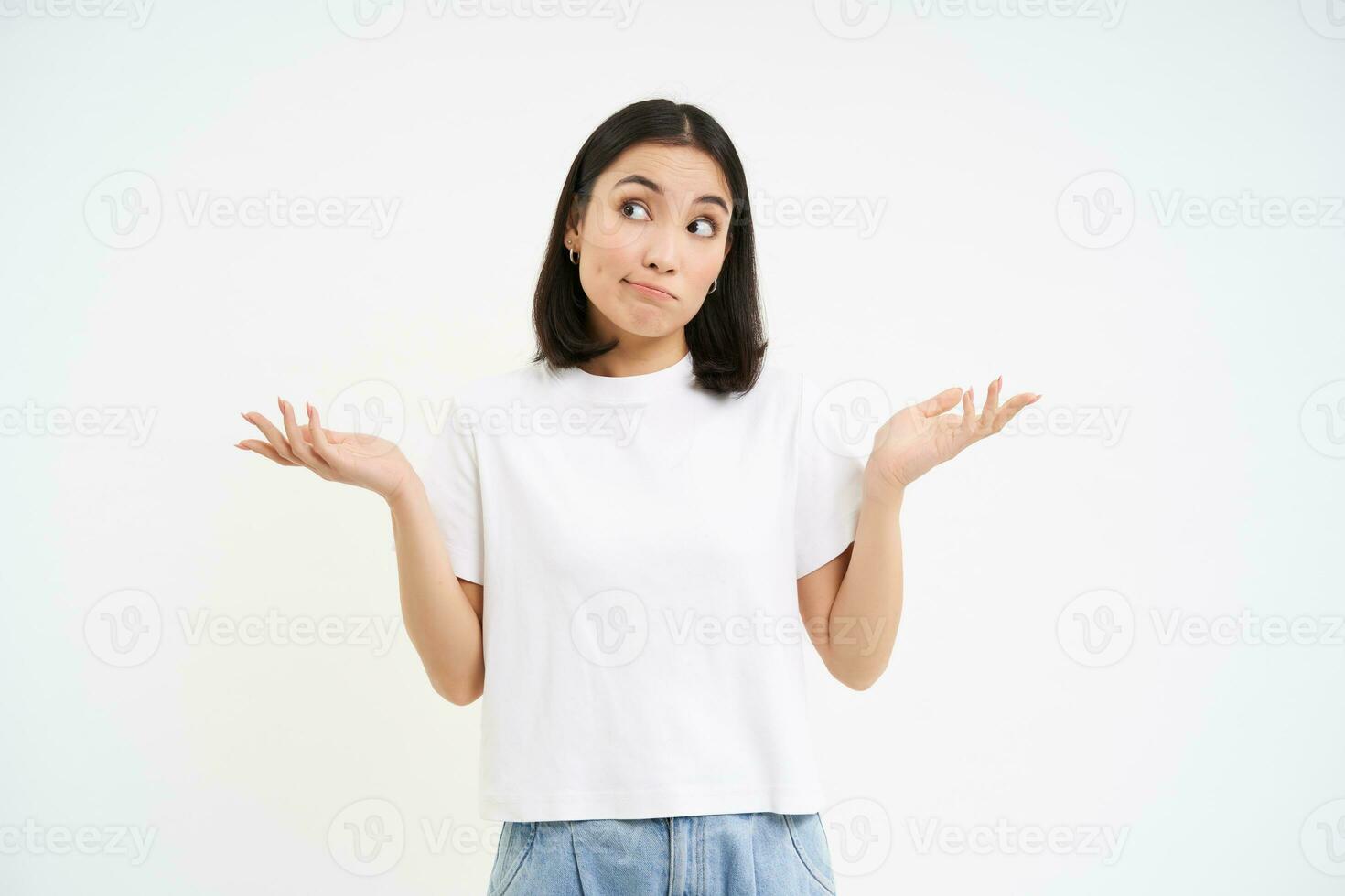 Portrait of confused korean woman, shrugging shoulders, looks puzzled, dont know, has no idea, stands over white background photo