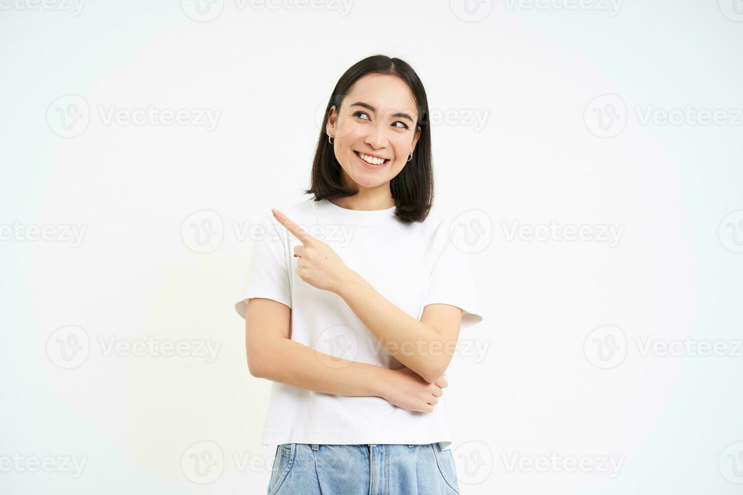 Portrait of beautiful smiling asian woman, pointing finger left, showing advertisement, recommending website, isolated on white background photo