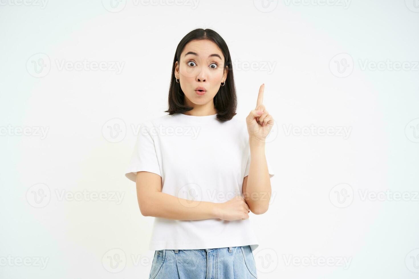 Eureka. Asian woman raises one finger, has suggestion, got an idea, pointing up, isolated against white background photo