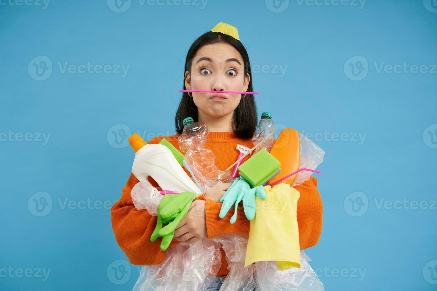 gracioso niña participación un montón de reciclaje basura, el plastico residuos a reciclar, azul antecedentes foto