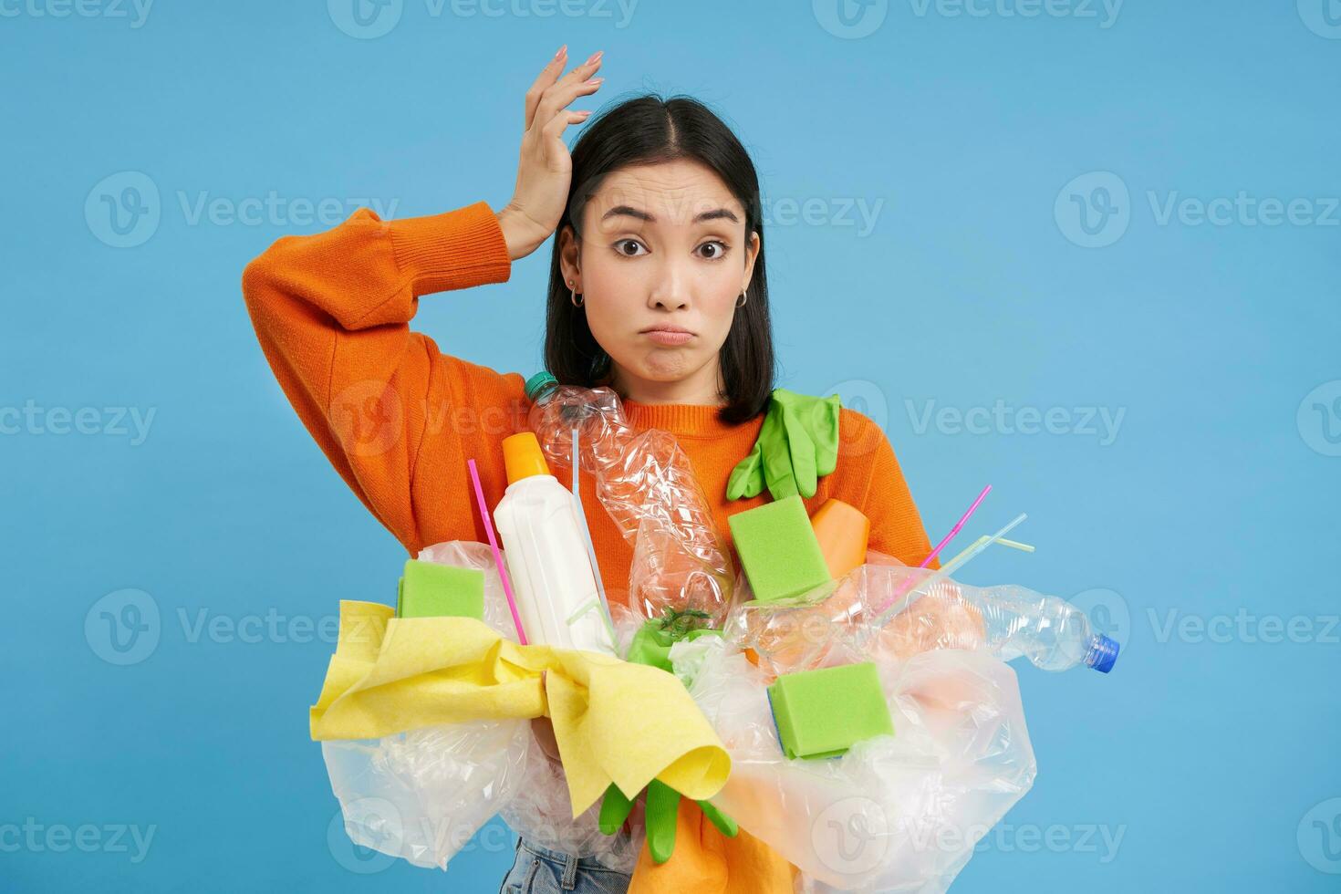 confuso coreano mujer intentos a Vamos verde, reciclar el plastico casa elementos, participación botellas y guantes, lo hace reciclaje, azul antecedentes foto