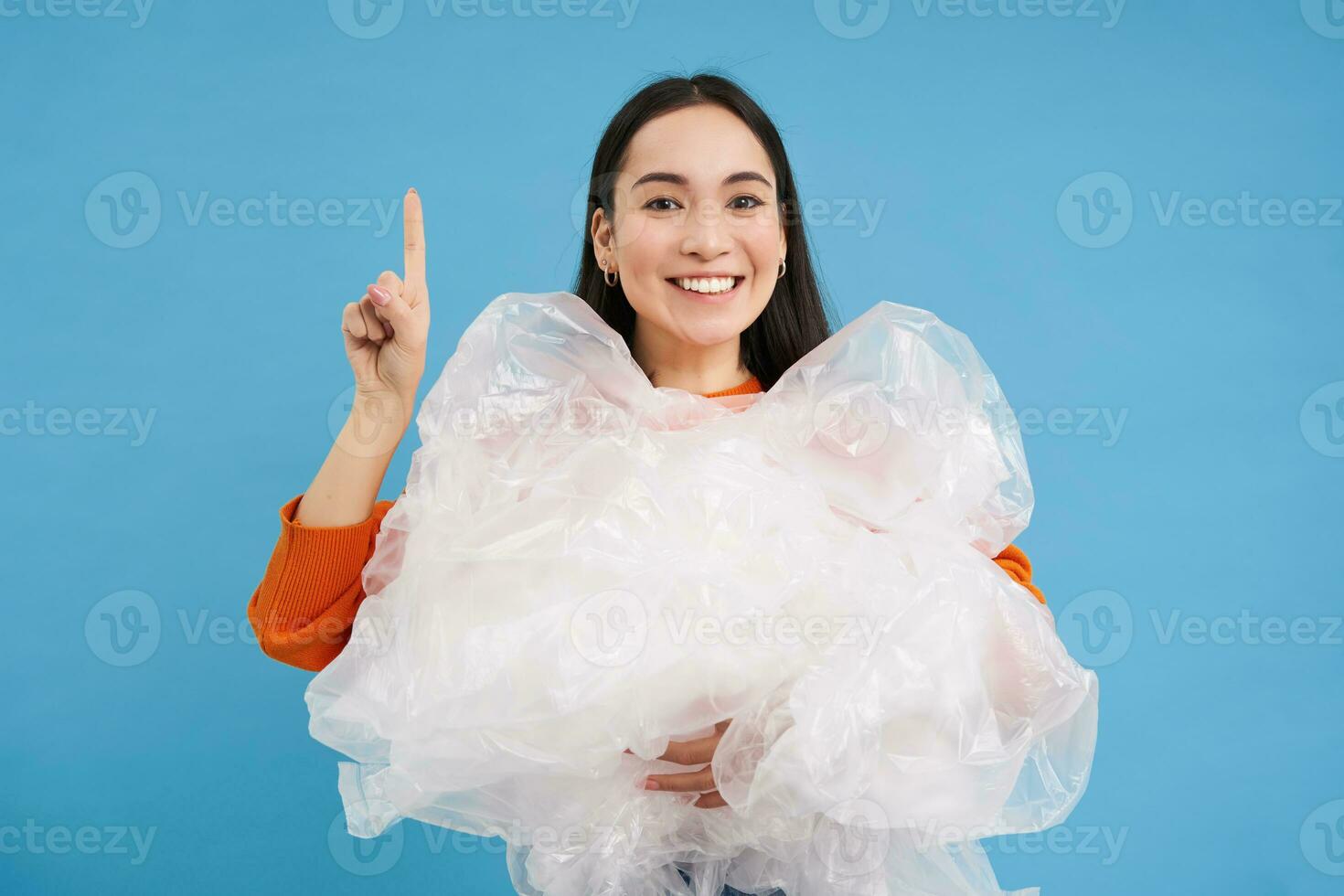 Asian woman with plastic bags, recycling waste in hands, points up ...