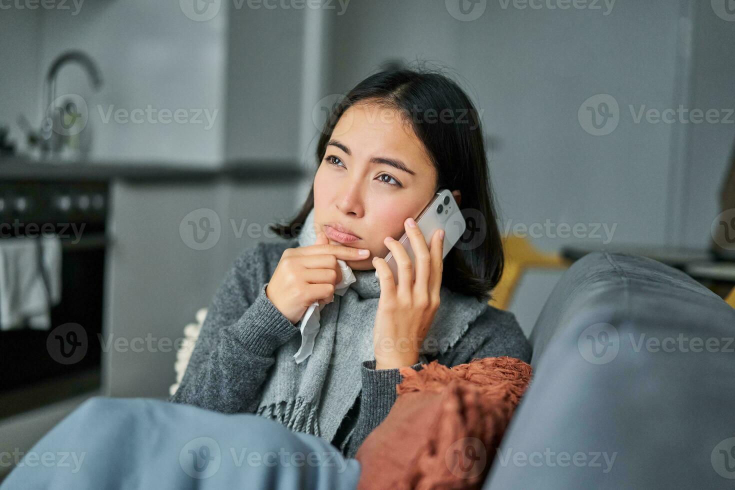 Portrait of sick woman calling her medical clinic, phone call appointment with GP, caught cold and stays at home photo