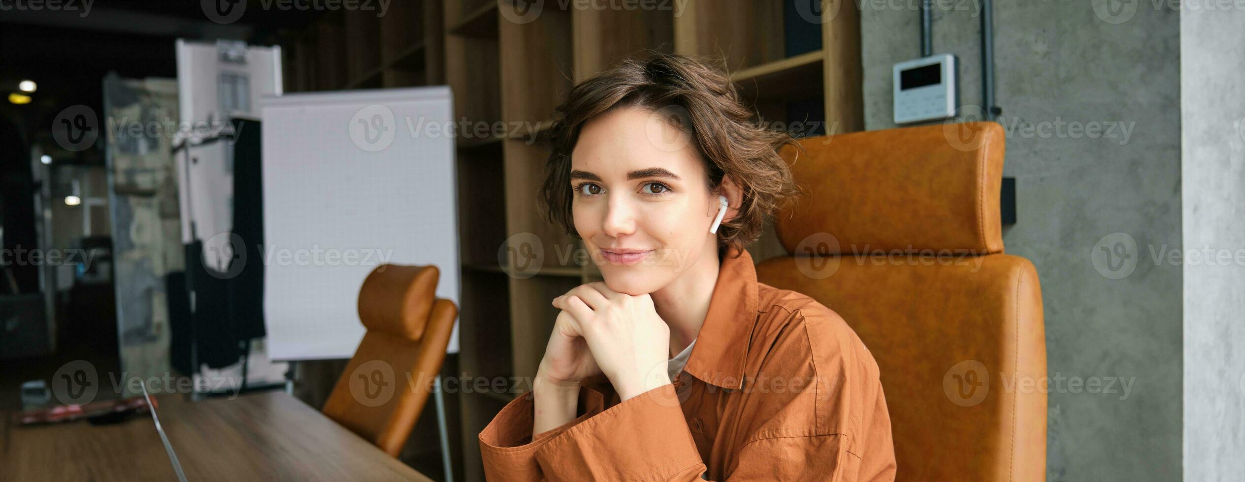 Portrait of young businesswoman in casual clothes, employee sitting in her office, smiling and looking at camera photo