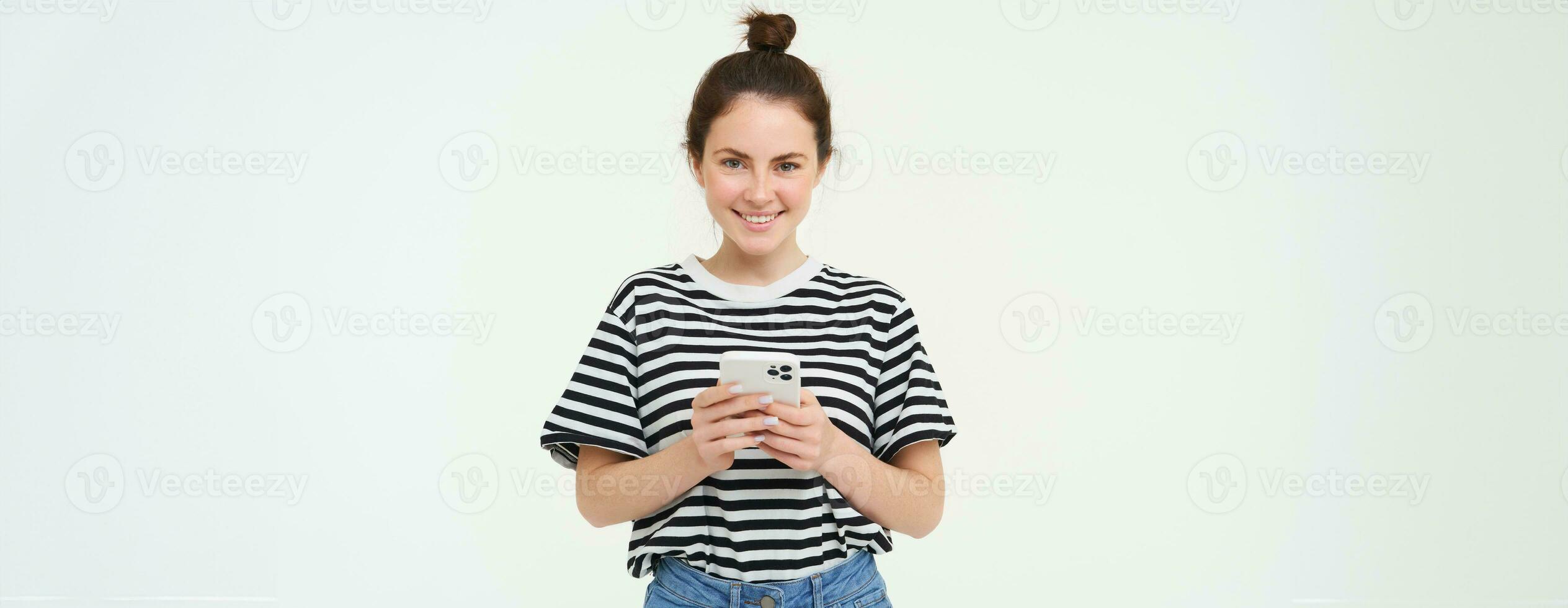 Technology and people concept. Young woman with mobile phone, smiling, using smartphone app, social media application, isolated over white background photo