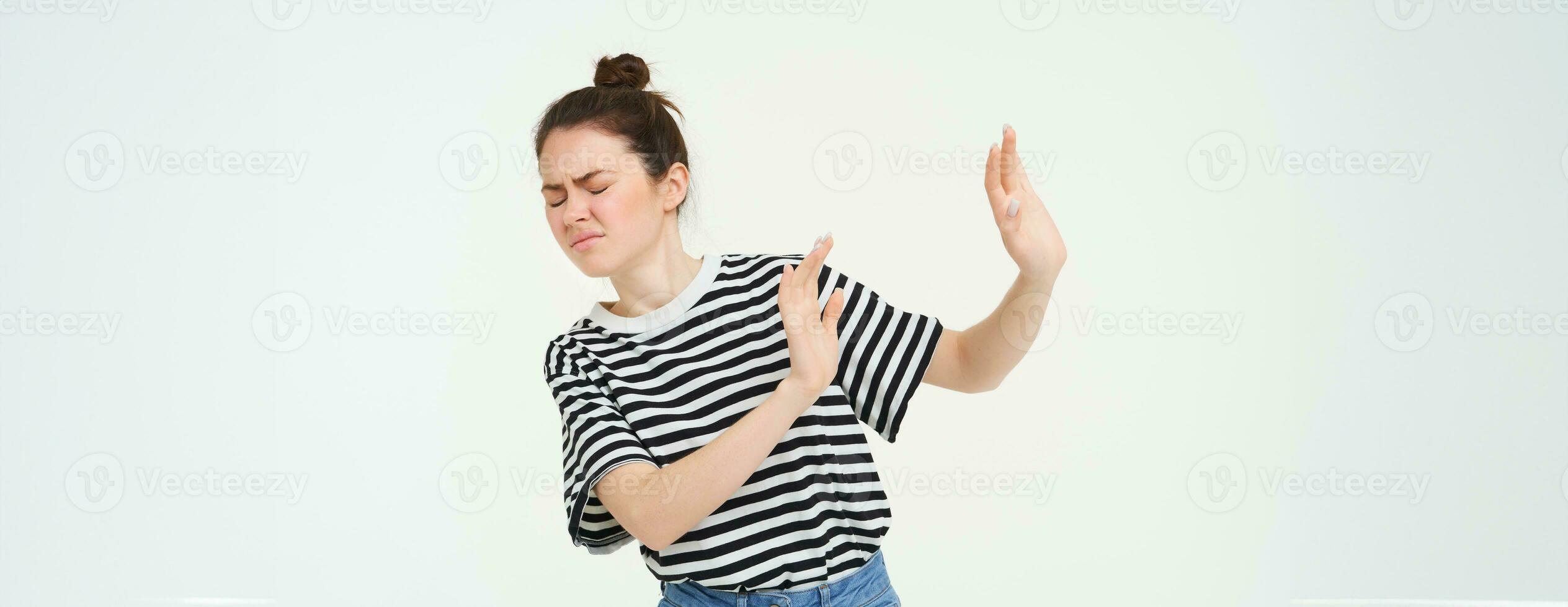 Portrait of woman looking disgusted, expressing dislike and aversion, raising hands to block something, rejecting offer, refusing, standing over white background photo