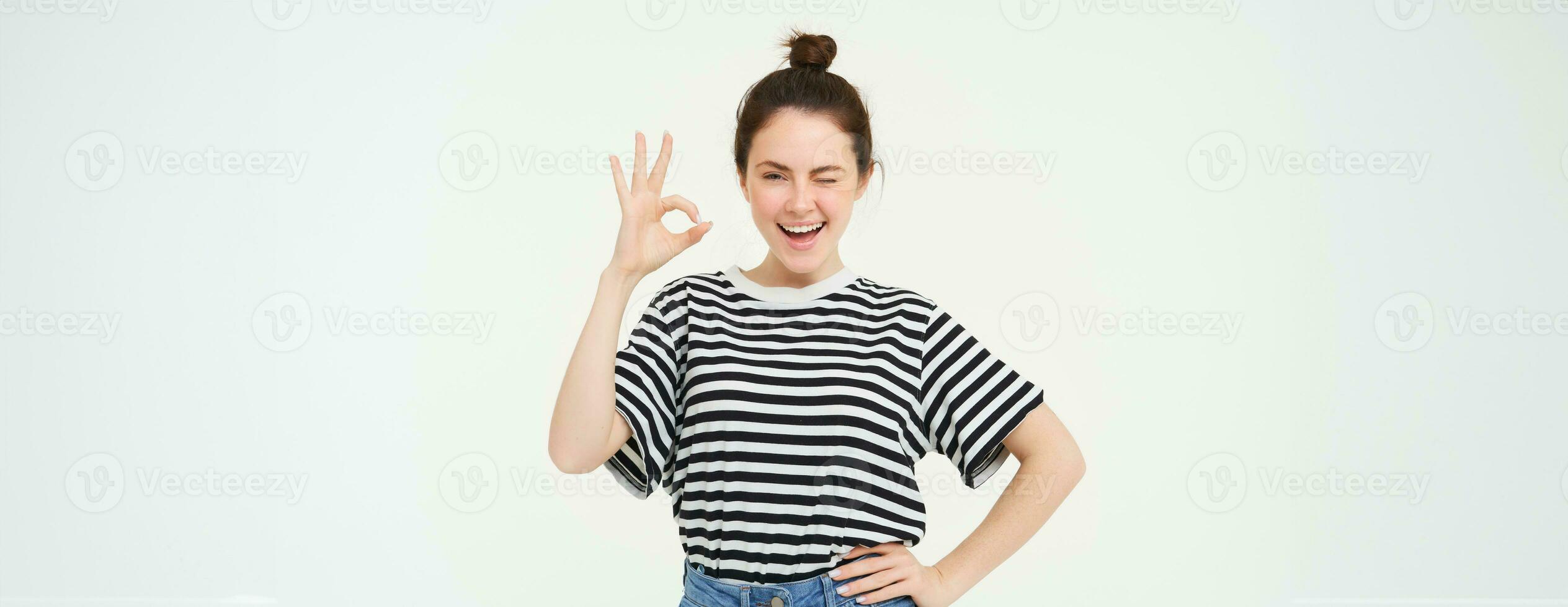 Excellent choice. Smiling stylish young woman, showing okay, ok gesture, zero sign, standing over white background photo