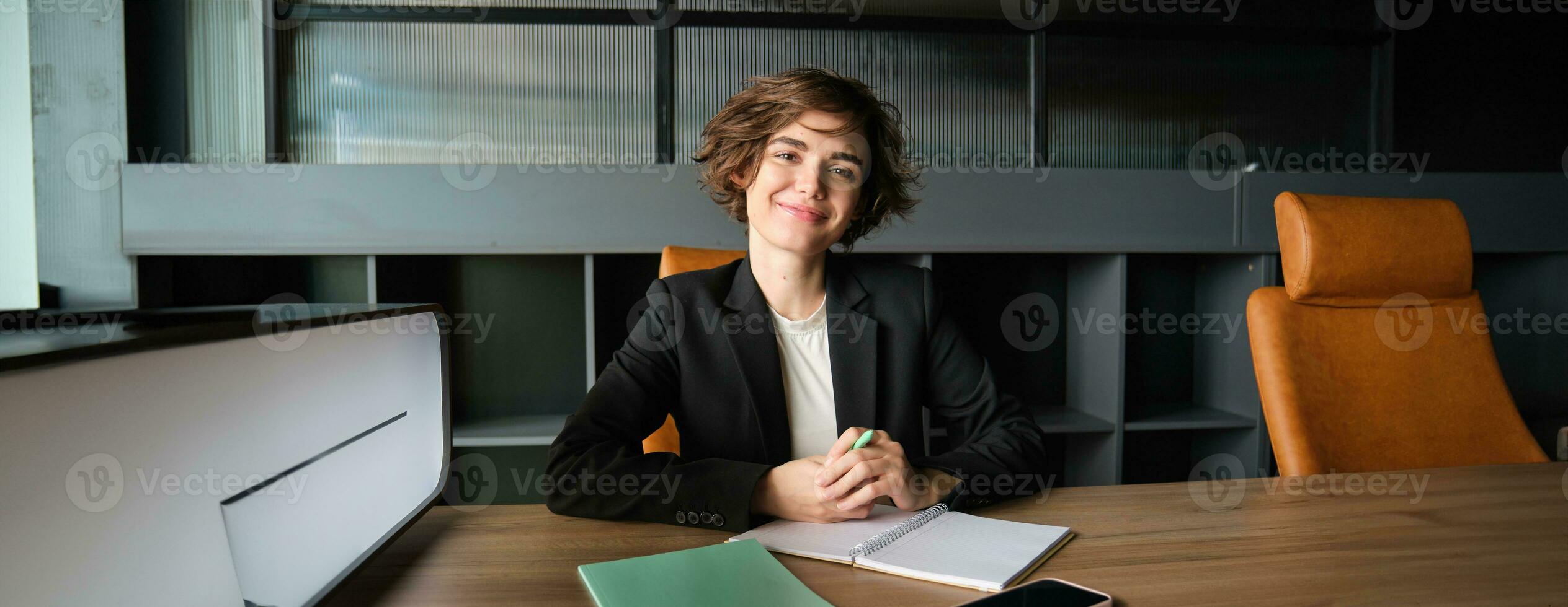 Portrait of young businesswoman working in her office, reading papers, studying documents of case and smiling, sitting in suit, having an interview photo