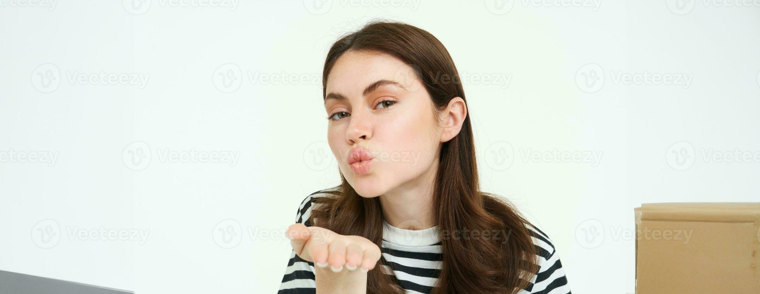 retrato de linda niña enviando tú, soplo aire beso, participación palma cerca fruncido labios, sonriente, en pie terminado blanco antecedentes foto