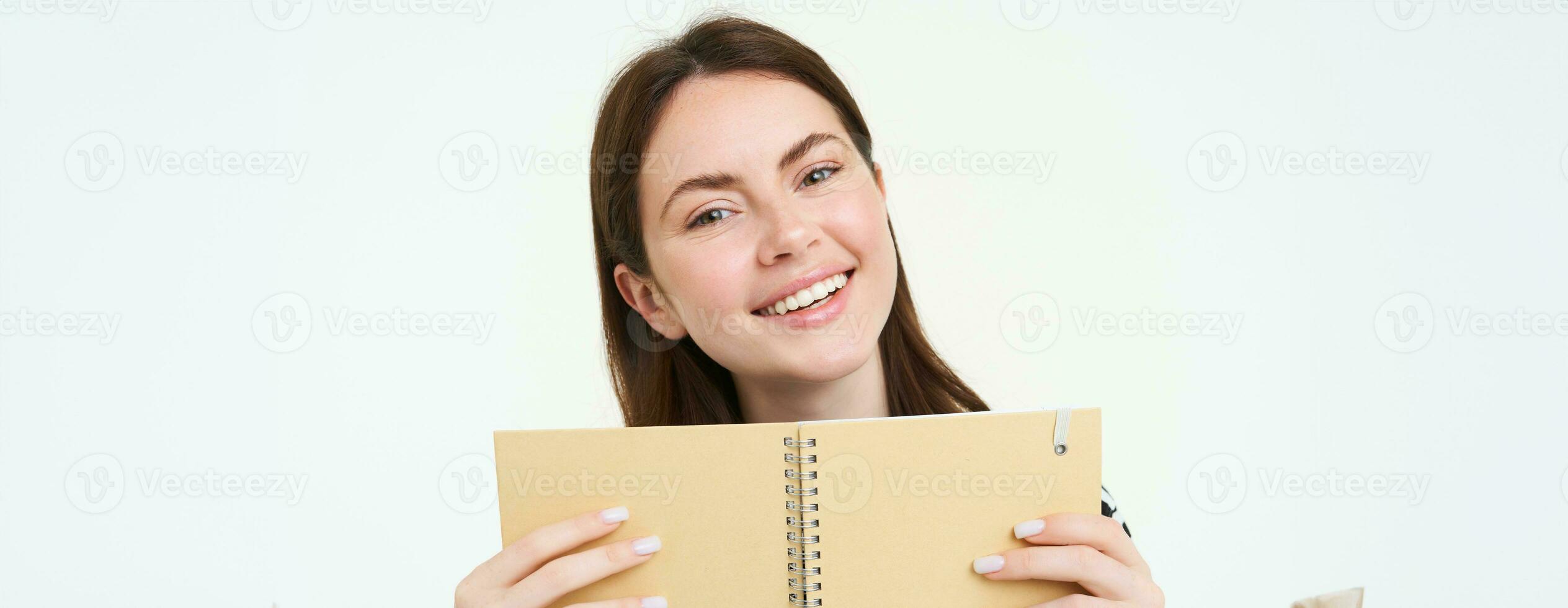 imagen de joven mujer con computadora portátil, participación su personal diario, trabajo planificador, sonriente, leyendo algo, en pie terminado blanco antecedentes foto