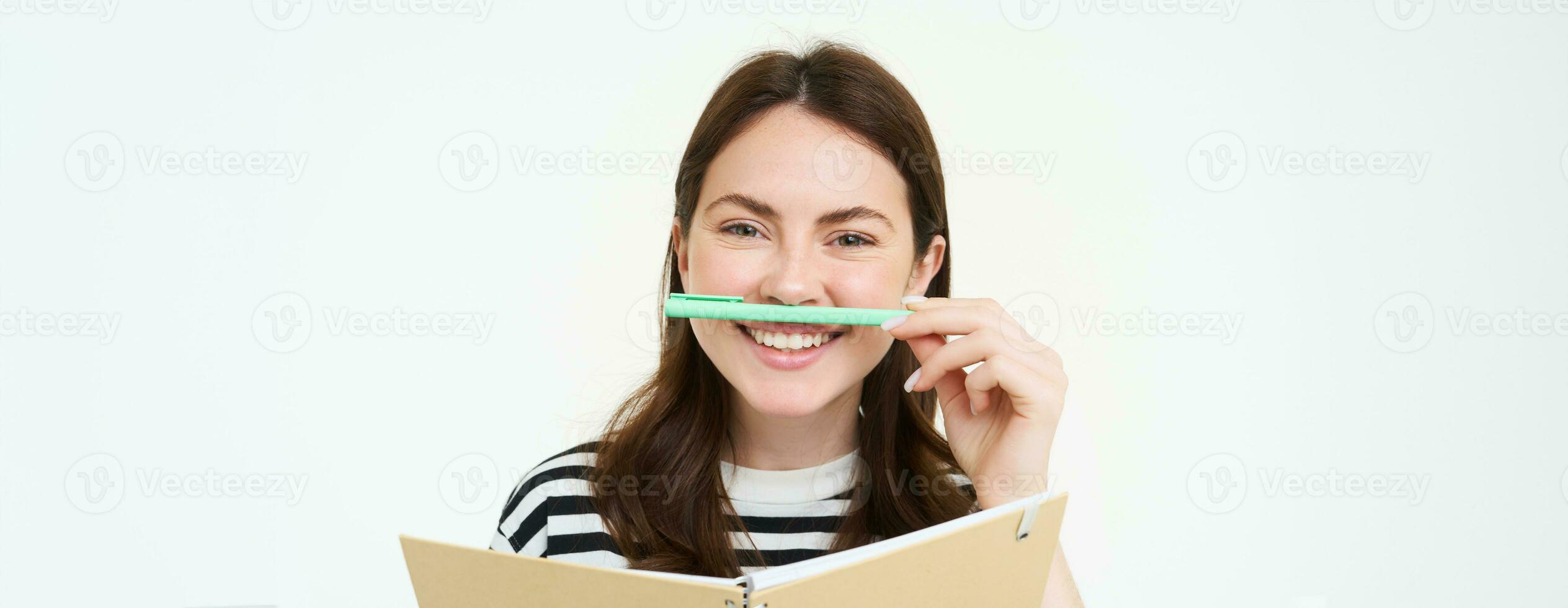 Image of beautiful young woman, student holding notebook, memo planner and pen, smiling and looking happy, isolated against white background photo