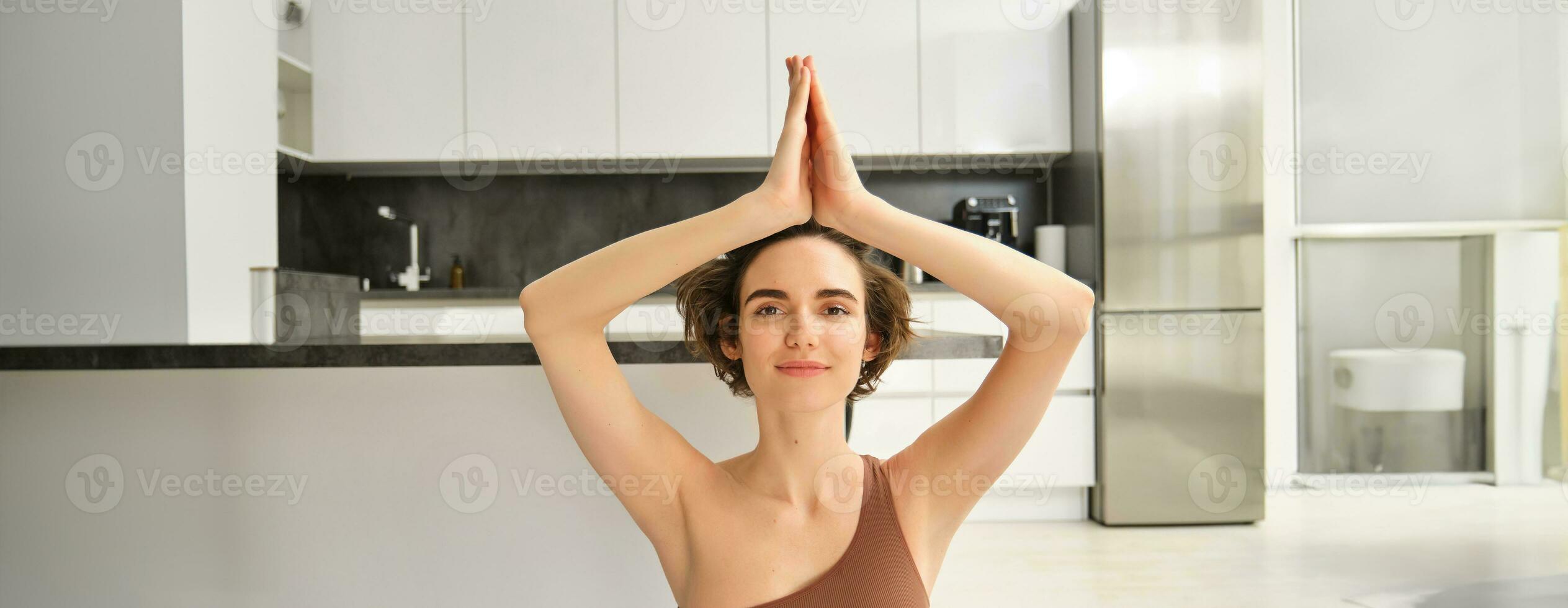 Portrait of fit and healthy woman in sportswear, doing yoga at home on fitness mat, making asana, relaxing and meditating indoors photo
