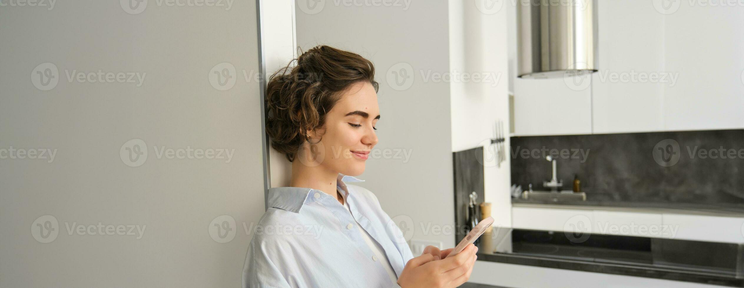 Portrait of brunette woman with smartphone, sending message, checking her mobile application, ordering delivery to home photo