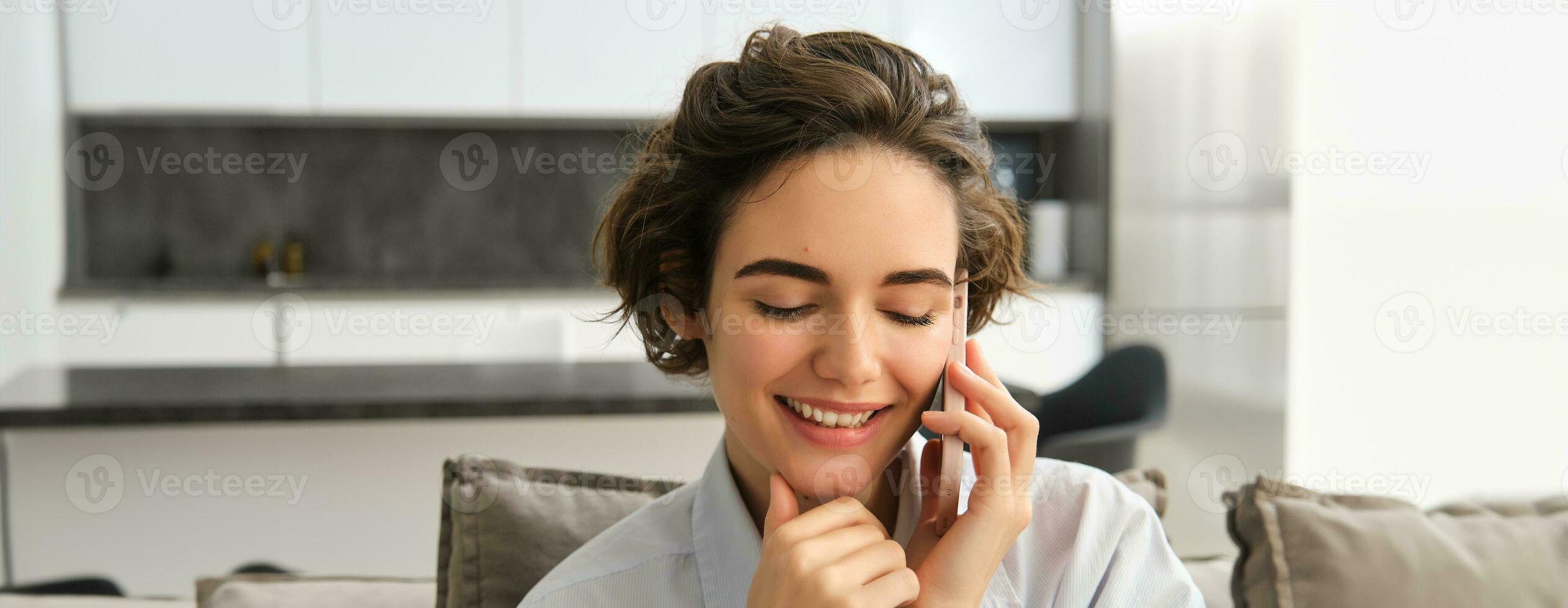 Close up portrait of smiling beautiful woman, talking on mobile phone, chats on smartphone, calls someone, sits at home photo