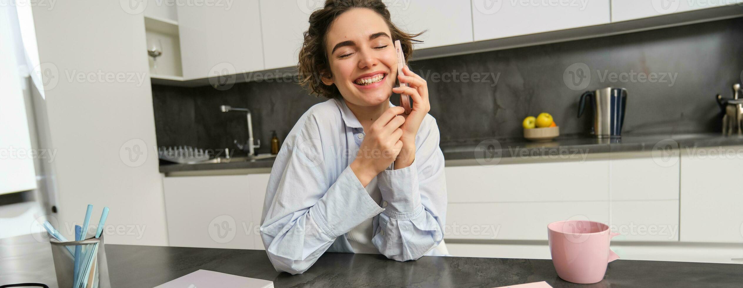 Portrait of cute smiling girl talks on mobile phone, sits at home and calls someone with smartphone photo