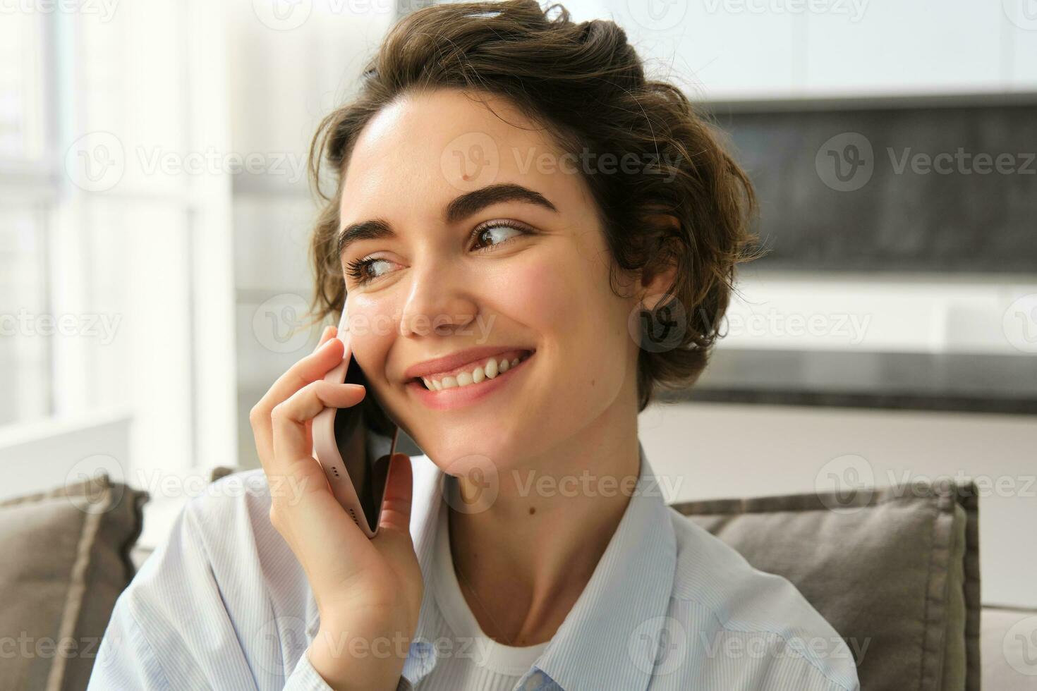 Close up portrait of smiling beautiful woman, talking on mobile phone, chats on smartphone, calls someone, sits at home photo