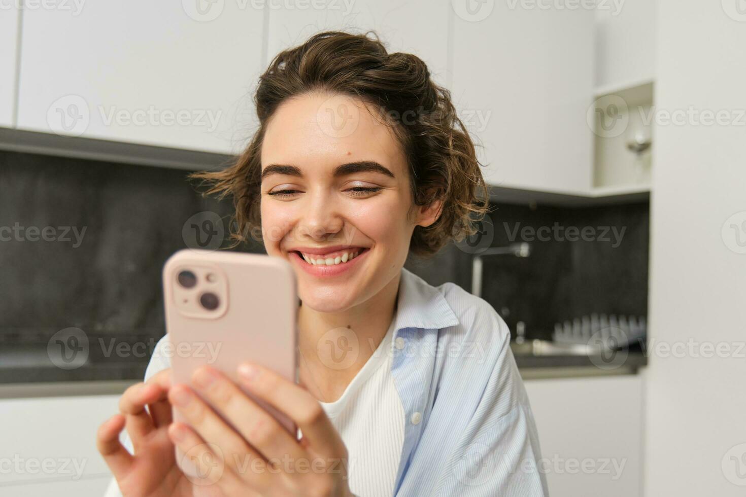 Portrait of beautiful woman at home, holding smartphone, online shopping from mobile phone app photo