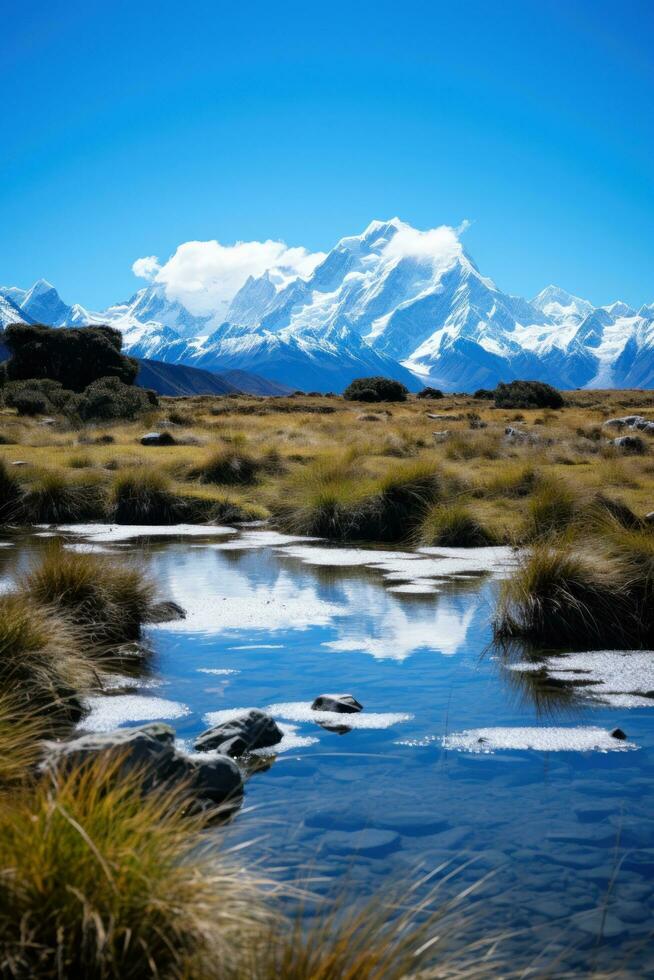 AI generated A serene mountain range with snow-capped peaks, a clear blue sky, and a tranquil lake in the foreground. photo