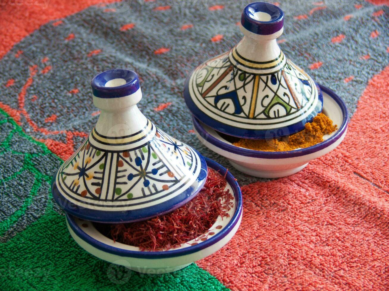 two small bowls with spices on a colorful table cloth photo