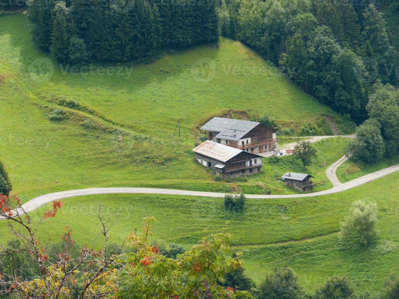 a house sits on a hillside in the middle of a green valley photo