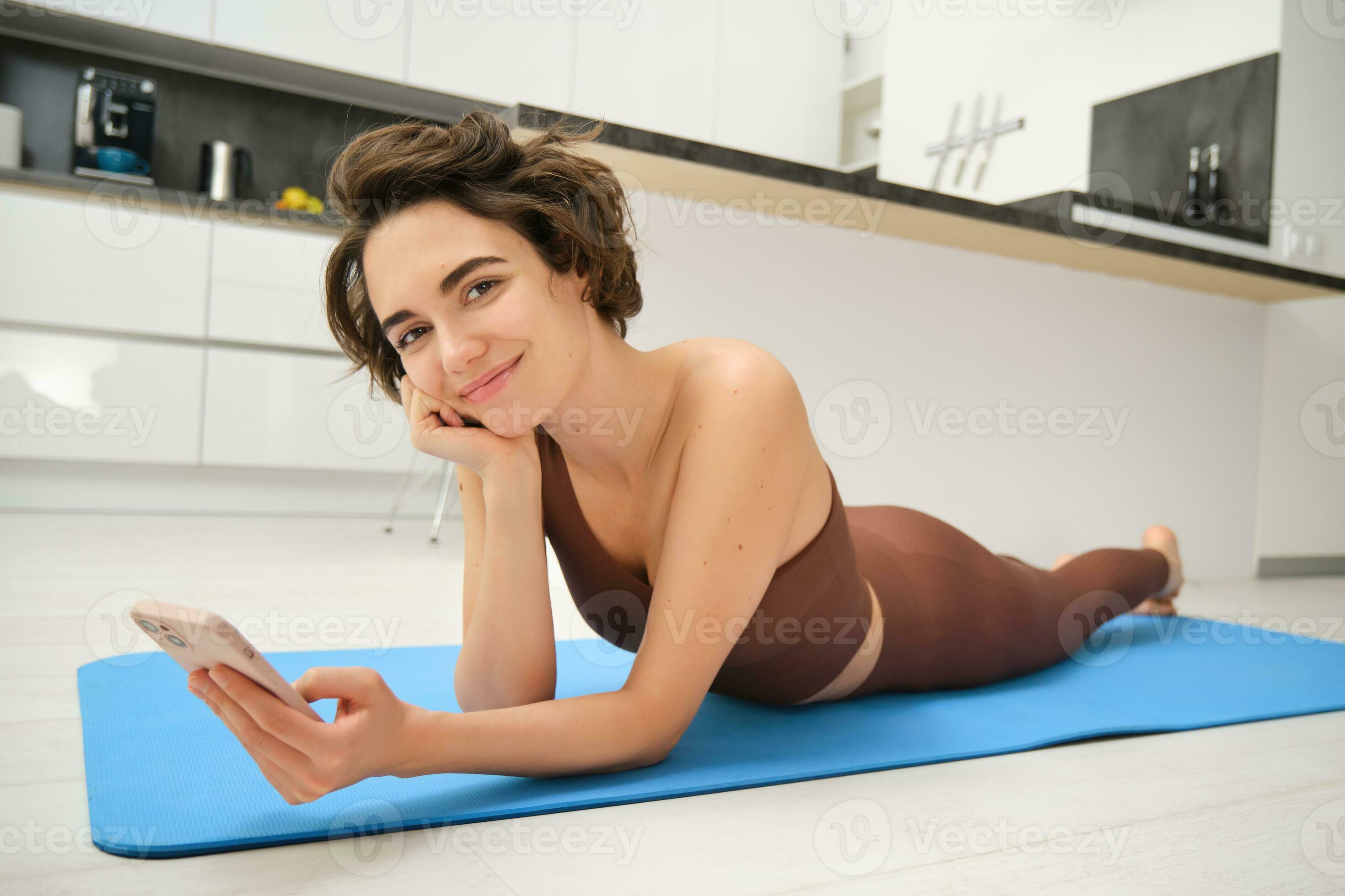 Cute brunette woman lying on yoga mat at home, doing fitness