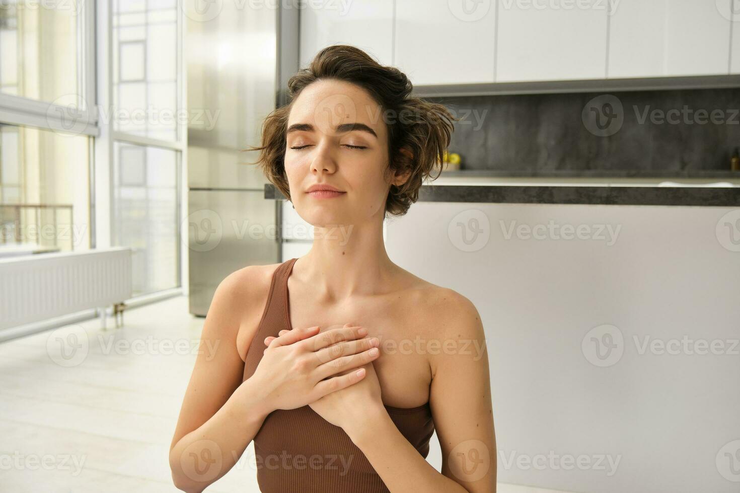 retrato de joven consciente de mujer, abre su chakra, haciendo yoga en caucho estera a hogar, cierra ojos y sonrisas, siente paz dentro su pecho. foto