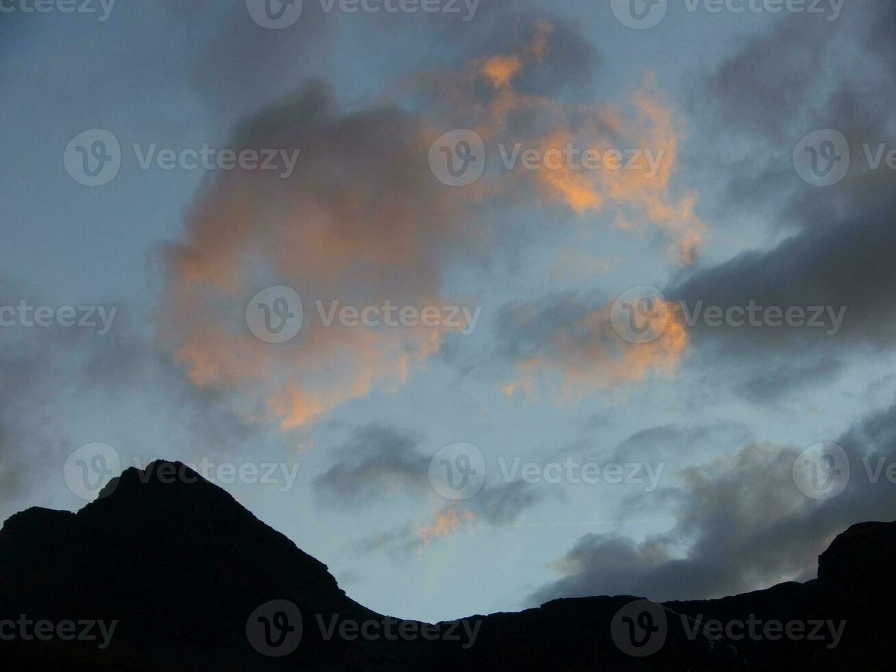 a sunset over the mountains with clouds in the sky photo