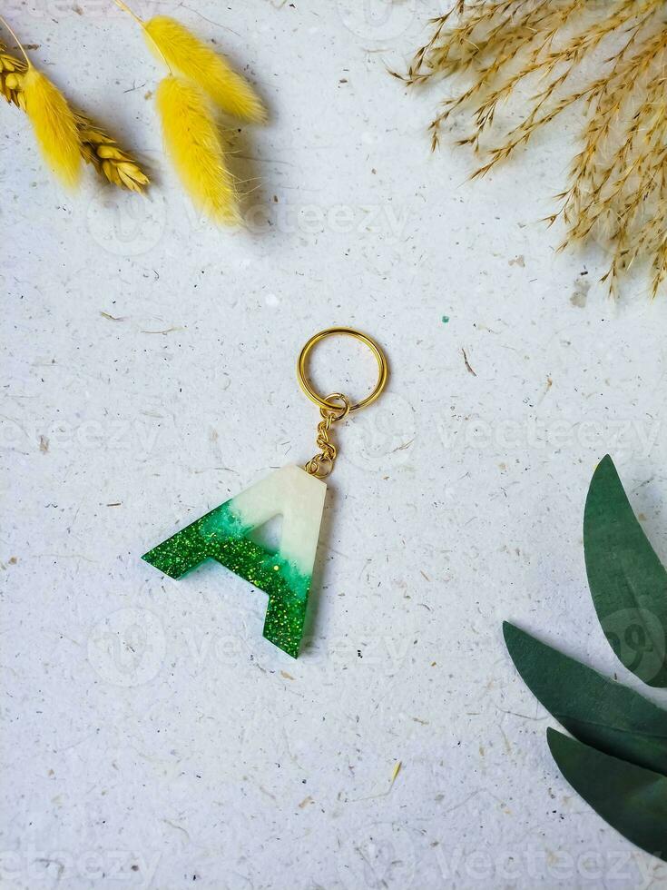 white and green alphabet resin key chain on a white background with copy space for text. Flat lay, top view. photo